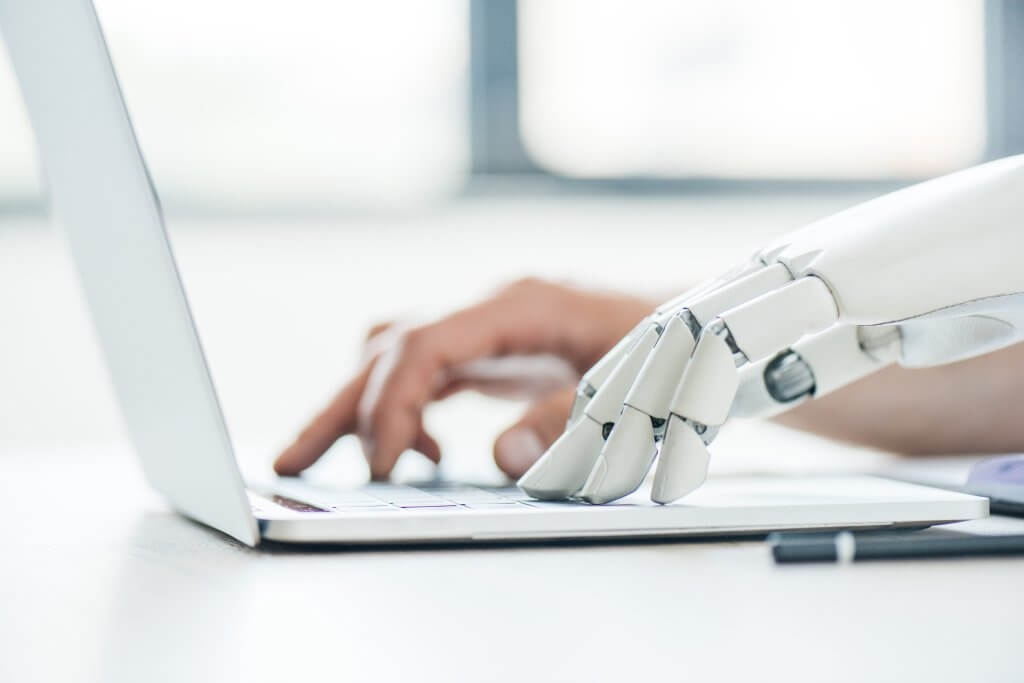 AI Robot hand and human hand typing on a computer