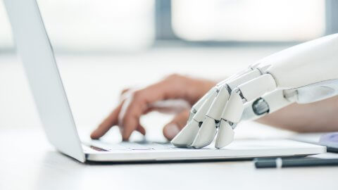 AI Robot hand and human hand typing on a computer